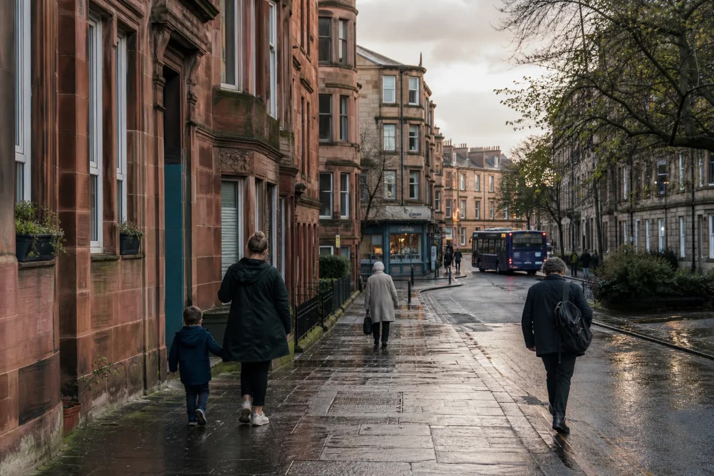 People walking along a wet Glasgow tenement street after rain